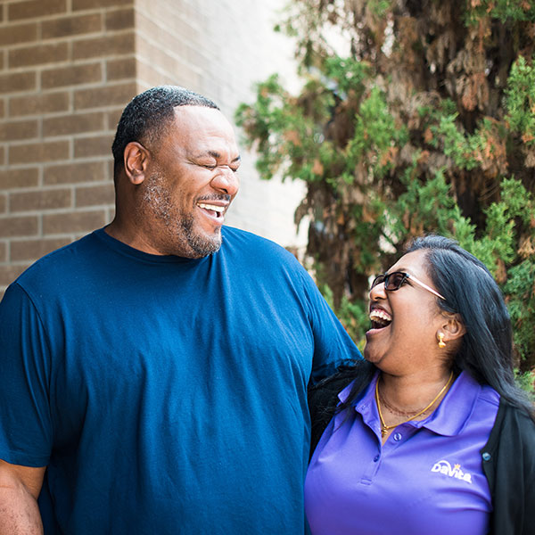 A man and woman share a joyful moment, laughing together outside a building, showcasing their happiness and connection.