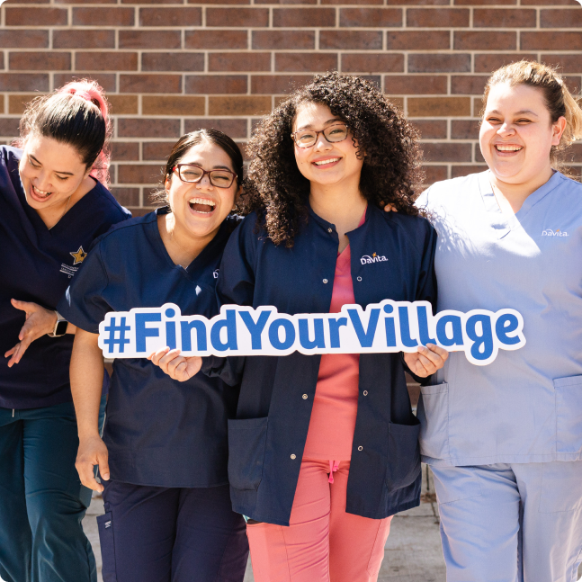 A group of teammates smiling and laughing while holding a #findyourvillage sign